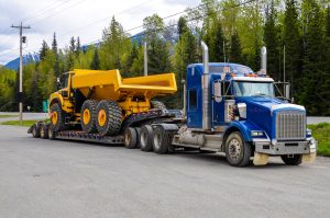 Gros camion avec une plate-forme basse portant un camion benne sur un parking public d'un arrêt de camion