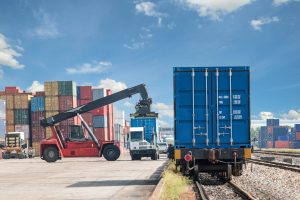 Chariot élévateur chargeant un conteneur sur un train de livraison